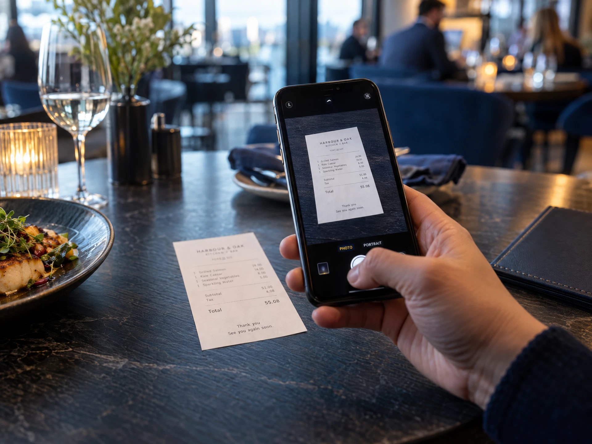 A printed restaurant receipt being photographed on a phone at a table